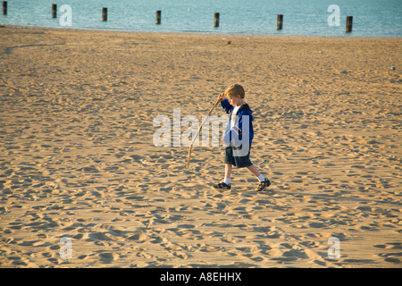 CHICAGO Illinois Young Boy laufen im Sand und Stick Strand entlang Lake Michigan See tragen Stockfoto