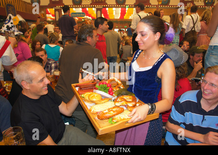 Server-Kellnerin tragen Tablett mit Brathähnchen oder gebratenem Fleisch um im Bierzelt auf Oktoberfest Bier Festival Stockfoto