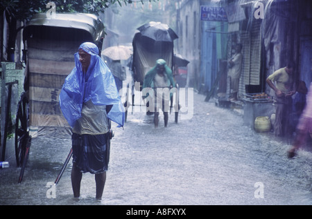 Rikscha-Fahrer auf der Suche nach Kunden in der Monsun, Kolkata, Westbengalen, Indien Saison Stockfoto