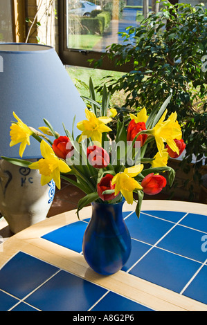 Eine bunte Anordnung von roten Tulpen und gelbe Narzissen in blauer vase Stockfoto