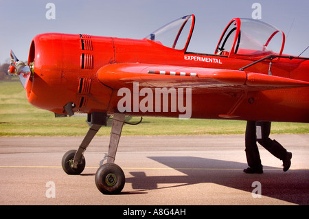 Flügelnuss: Ein leuchtend rotes Flugzeug scheint Beine zu haben, als ein Pilot sein Flugzeug namens 'Experimental' auf einer Landebahn am Shoreham Airport, West Sussex, Großbritannien, schiebt Stockfoto