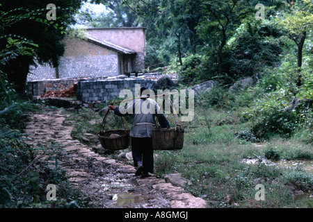 Person, die Körbe einen Stein Weg in einer ländlichen Gegend in der Nähe von Guilin, China Stockfoto