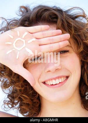 Teenager-Mädchen lächelnd mit Abbildung einer Sonne in Sonnencreme auf ihre helle Haut von Hand gezeichnet muss gegen UV-Strahlen geschützt werden Stockfoto