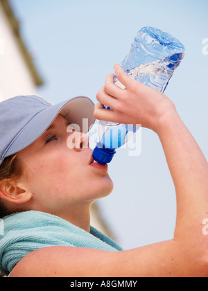 Teenager-Mädchen junge Frau trinkt Mineralwasser sportlichen look vertikale Stockfoto