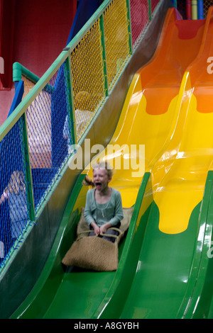 Mädchen auf einer farbigen Folie in einem indoor-Spielplatz sausen Stockfoto