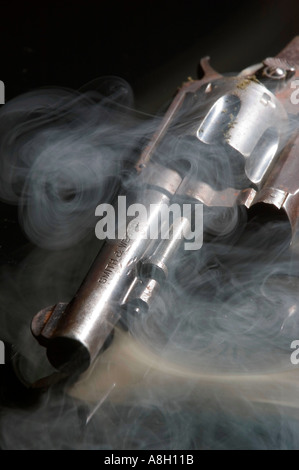 Verrostete Smith Wesson 38 Kaliber Revolver Pistole mit Rauch auf reflektierenden schwarzen Hintergrund Studio Stillleben Stockfoto