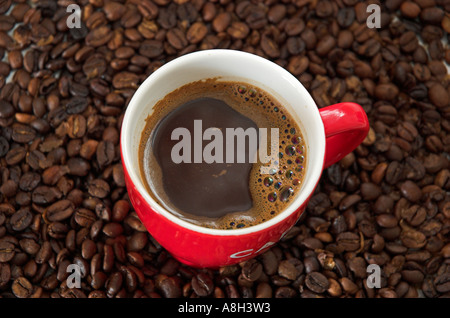 Rote Tasse schwarzen Kaffee ruht auf Kaffeebohnen erhöht, Ansicht Stockfoto