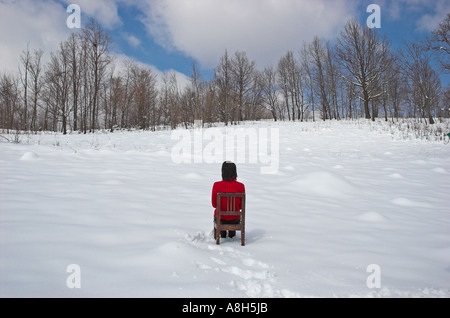 Junge Frau sitzt auf dem Stuhl im Schnee Stockfoto
