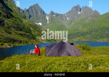 Herr Jüngling sitzt an seinem Zelt in der Wildnis von Moskenesoya mit Agvatnet und Mannen Lofoten Norwegen Stockfoto