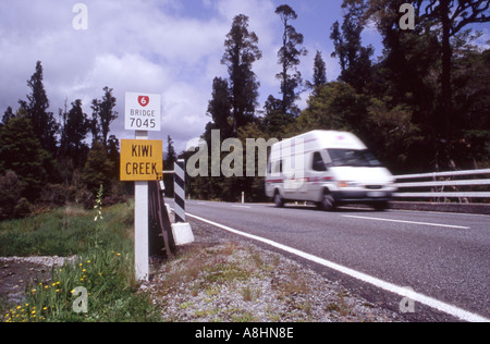 Am Straßenrand Zeichen Kiwi Creek mit einem vorbeifahrenden Campervan Haast Pass West Coast-Neuseeland Stockfoto