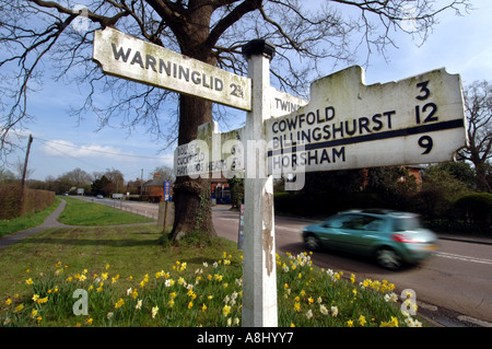 Ein Auto beschleunigt vorbei an einer alten hölzernen Schild auf die A272 Bolney Sussex auf dem Weg nach Horsham Stockfoto