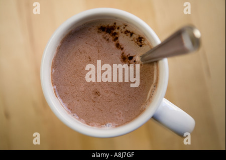 Eine weiße Tasse mit heißer Schokolade und einem Teelöffel steht allein auf einem Holztisch Oberfläche, Februar 2006 Stockfoto