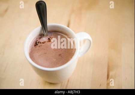 Eine weiße Tasse mit heißer Schokolade und einem Teelöffel steht allein auf einem Holztisch Oberfläche, Februar 2006 Stockfoto