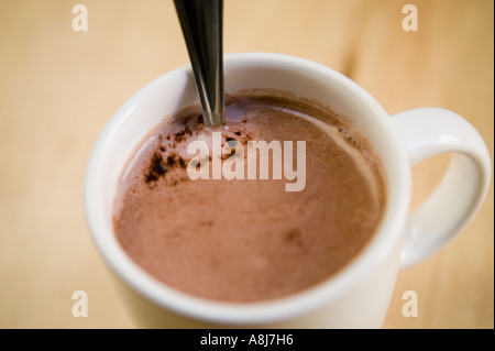 Eine weiße Tasse mit heißer Schokolade und einem Teelöffel steht allein auf einem Holztisch Oberfläche, Februar 2006 Stockfoto