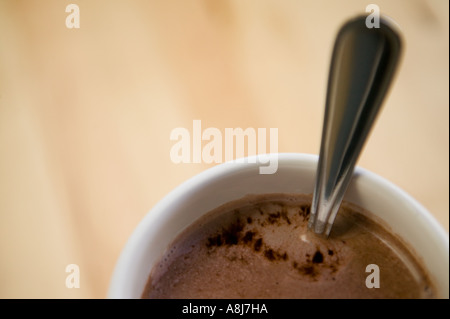 Eine weiße Tasse mit heißer Schokolade und einem Teelöffel steht allein auf einem Holztisch Oberfläche, Februar 2006 Stockfoto