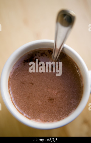 Eine weiße Tasse mit heißer Schokolade und einem Teelöffel steht allein auf einem Holztisch Oberfläche, Februar 2006 Stockfoto