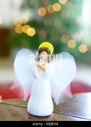 Weißer Kunststoff Engel mit Flügeln infront des Weihnachtsbaums auf Tisch stehend Stockfoto