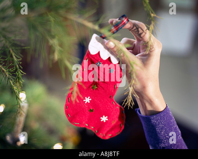 Person putzt den Weihnachtsbaum mit einen roten handgemachte Dekoration Strumpf Stockfoto