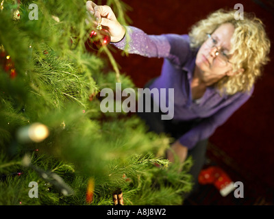 Person putzt den Weihnachtsbaum mit einer roten Kugel Dekoration erschossen von oben Stockfoto