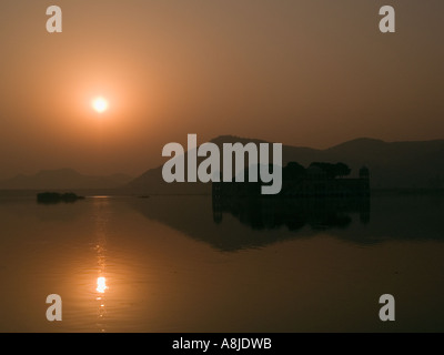 See Mansagar bei Sonnenaufgang mit Jal Mahal und Aravali Bergkette Silhouette durch goldene Sonnenlicht. Jaipur Rajasthan Indien Asien Stockfoto