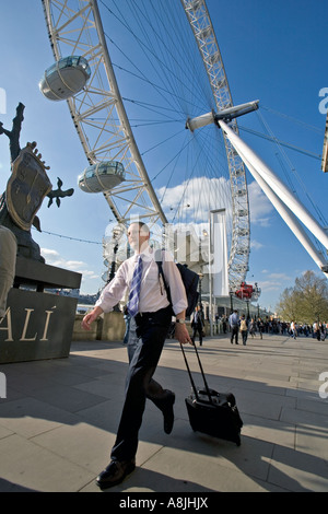 ein Mann Räder seinen Koffer hinter dem London Eye am Südufer der Themse Stockfoto