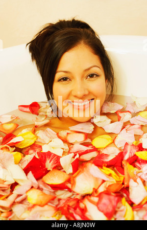 Porträt einer jungen Frau in einer Badewanne voller Blütenblätter Stockfoto