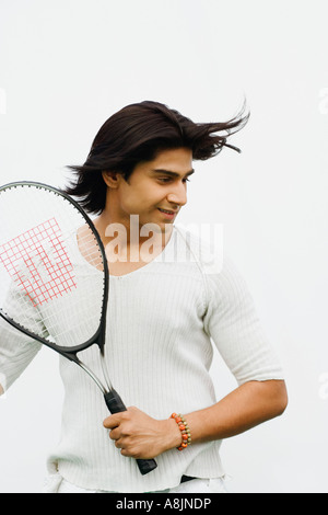 Junger Mann hält einen Tennisschläger und lächelnd Stockfoto