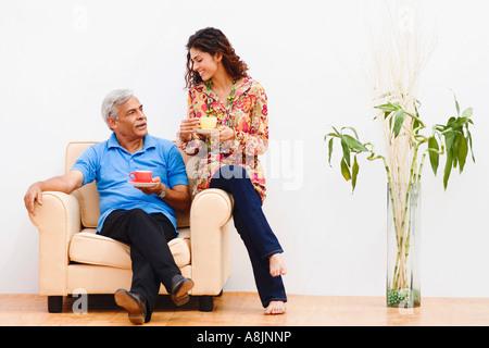 Junge Frau und ihr Großvater in einem Sessel sitzend und lächelnd Stockfoto