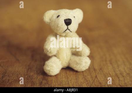 Kleinen Teddybär sitzend auf einem Holzsitz oder Tisch Stockfoto