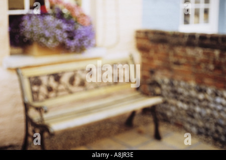 Impressionistischen Blick auf Sitzbank in eine intime Rücken oder Vorgarten mit Ziegel und Feuerstein Wand- und Fenster-Box beladen mit Blumen Stockfoto