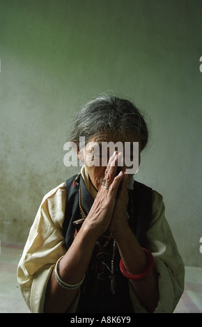 Eine tibetische Exil-Frau begrüßt Besucher mit einem Namaste-Geste, ihre Hände in einem Gebet Positionen in Indien. Stockfoto