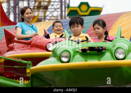 Mutter und Kinder freuen sich über die Astro Fighter ritten Genting Highlands Outdoor Freizeitpark, Malaysia Stockfoto