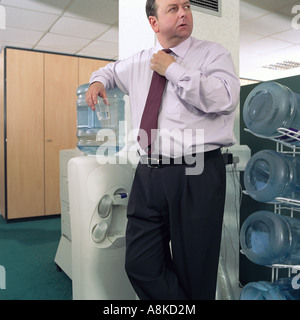 Ein Geschäftsmann stützte sich auf einen Wasserspender Stockfoto