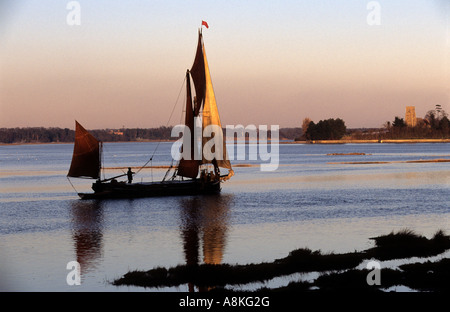 Segeln Schiff Cygnet auf dem Fluß Alde, mit St Botoph Kirche am Vorgewende, Iken, Suffolk, UK. Stockfoto