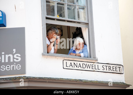 Leute, die sich aus einem Fenster der Mayday Obby Oss Festival Padstow Cornwall England UK Europa Stockfoto