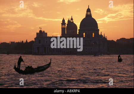 Gondeln auf dem Canale Grande bei Sonnenuntergang vor der imposanten Kirche von Santa Maria della Salute in Venedig, Italien. Stockfoto