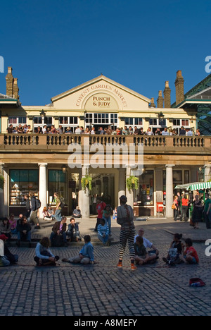 Vertikale hautnah von Menschen, die durch ein Straßenkünstler auf der Piazza in Covent Garden an einem sonnigen Abend unterhalten. Stockfoto