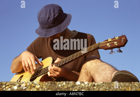 Mann spielt Gitarre draußen auf einem alten bunker Stockfoto