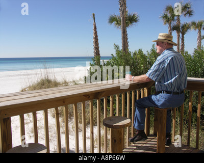 Mann, sitzend auf Stuhl suchen Out am Strand Stockfoto
