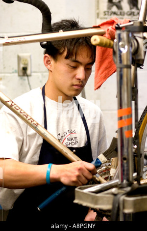 Asiatisch-amerikanische Arbeiter eine Reparatur auf einen Fahrradrahmen. Jugend Express Fahrrad Shop St. Paul Minnesota USA Stockfoto