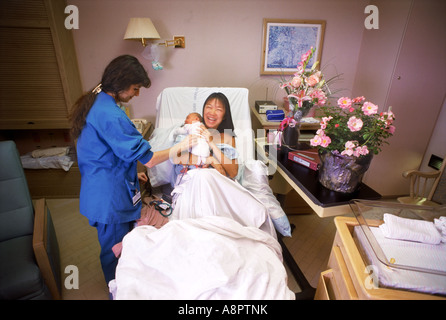 Krankenschwester, die tendenziell glücklich stolze Mutter und ihr Neugeborenes im Krankenhaus Aufwachraum Stockfoto