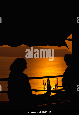 Griechenland Kykladen Inseln Santorini Fira Thira paar bei Sonnenuntergang im Meer bar Stockfoto