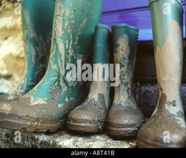 eine Familie von Gummistiefel vor der Haus Tür in der Landschaft mit grünen schlammigen Stiefel Stockfoto