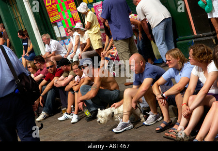 Besucher in Brecon Jazz Festival auf einen am Straßenrand Bordstein entspannen in der Sonne sitzen Stockfoto