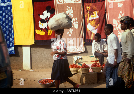 Tomaten und Handtücher zum Verkauf an einem Accra-Markt. Die Handtuch-Designs umfassen Mickey Mouse und eine spärlich bekleidete Frau. Stockfoto