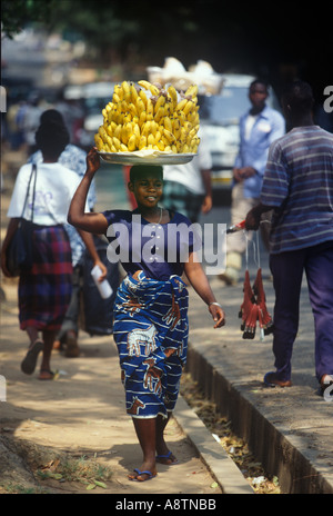 Ein Händler ihre Last von Bananen auf dem Kopf trägt geht auf dem Weg zum Markt in Accra Ghana Stockfoto