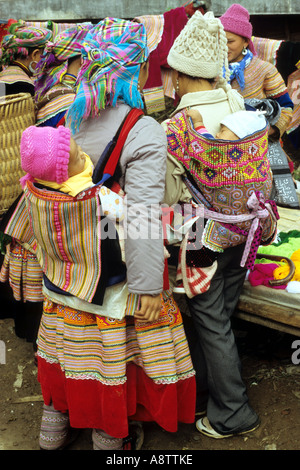 Flower Hmong Frauen in traditionellen und modernen Kleid, mit Babys im hinteren Träger Markt Sonntag, Bac Ha, NW Viet Nam Stockfoto