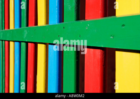 Bunte Reihen von Holz auf einem Spielplatz Zaun farblich gelb grün blau und rot lackiert Stockfoto