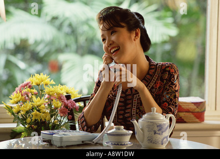 Singapur. Junge Frau zu Hause, die am Telefon spricht. Stockfoto