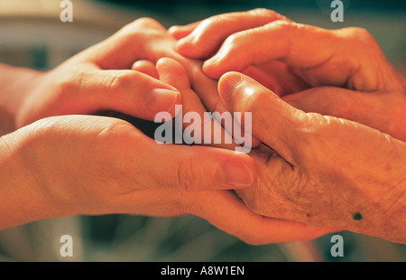 Nahaufnahme von alter Frau und jungem Mann, der Hände hält. Stockfoto